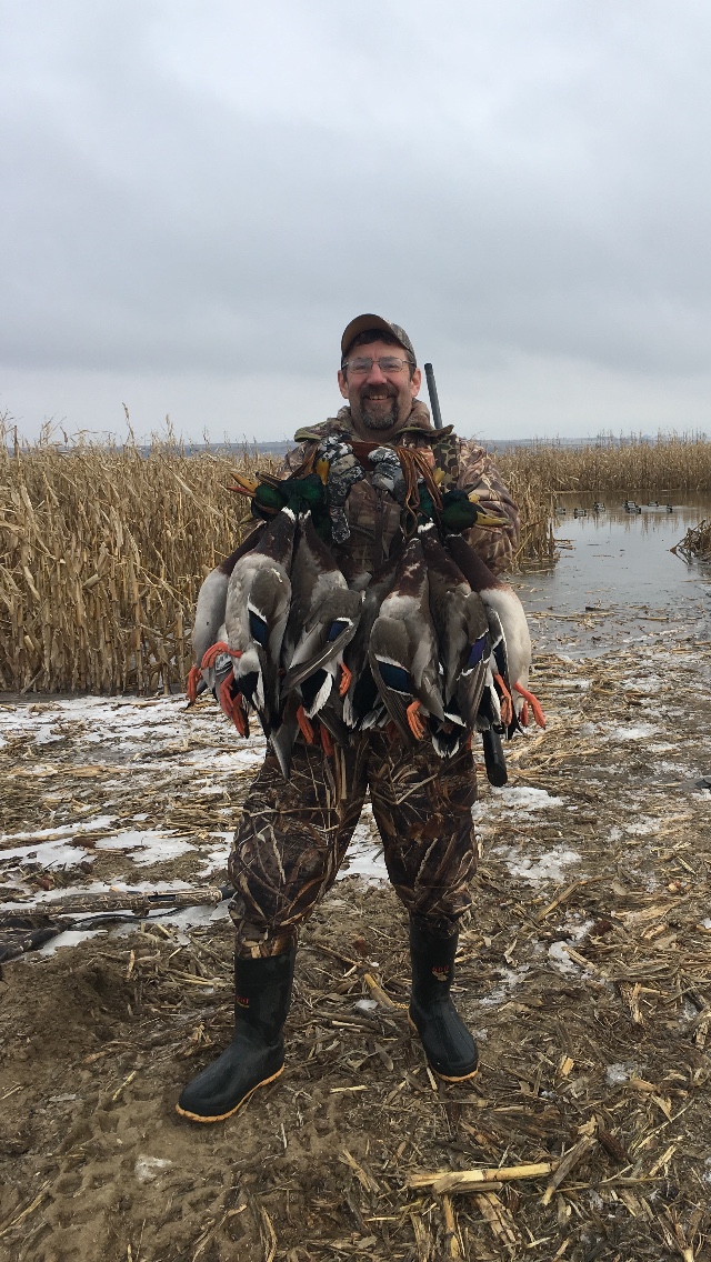 Tom Anderson with a strap of ducks in a marsh